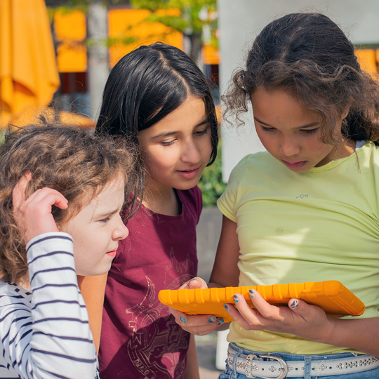 Drei Mädchen schauen gemeinsam auf ein Tablet