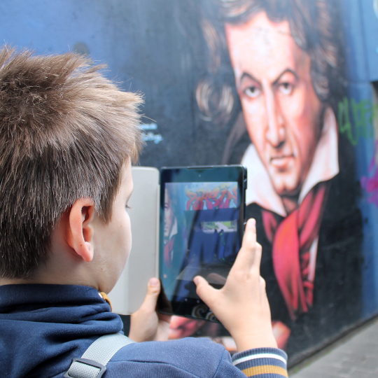 Eine Junge fotografiert eine Wandmalerei von Beethoven