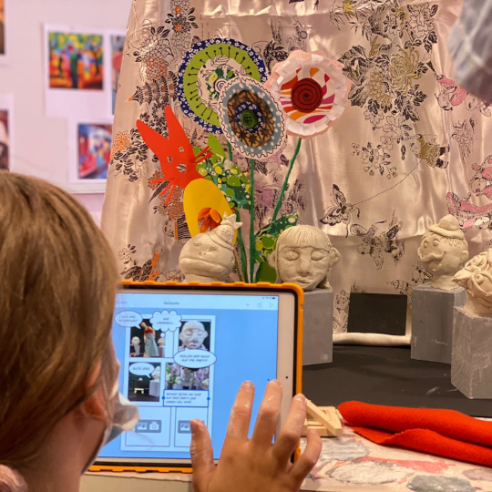 Ein Kind vergleicht Fotografien auf dem Tablet mit einem Ausstellungsstück im Museum