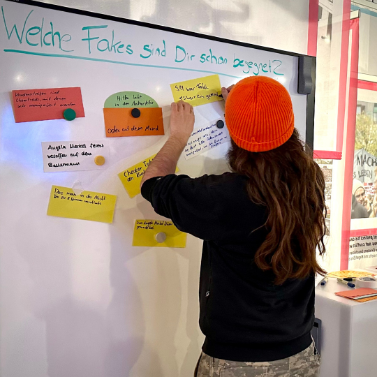 Eine Kindergruppe sitzt vor einem Elefanten im Museum König und hört einem Erwachsenen zu