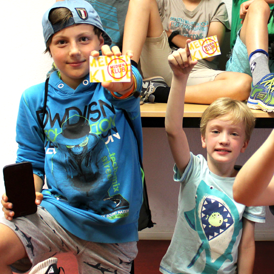 Kinder halten Karten ins Bild auf denen Medienklub steht