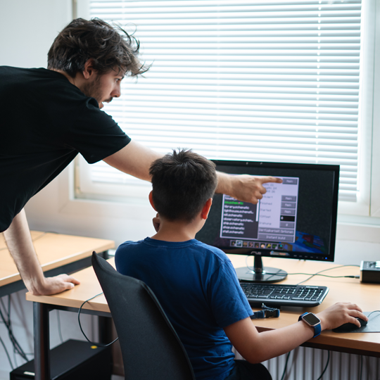 Dozent zeigt Teilnehmer das Programmieren am Computer