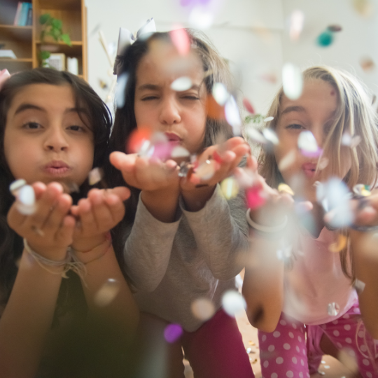 Kinder pusten Konfetti in die Kamera