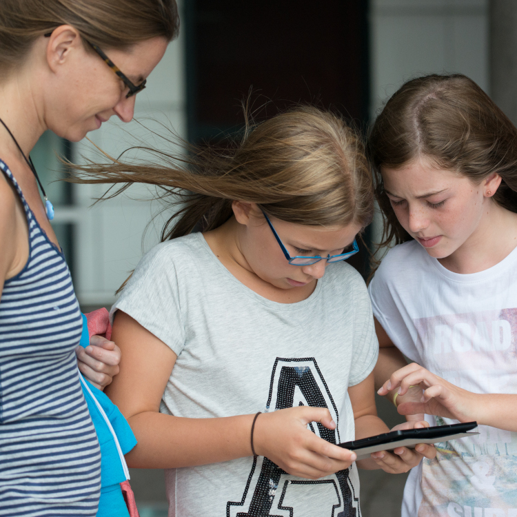Mutter und zwei Mädchen schauen auf ein Tablet