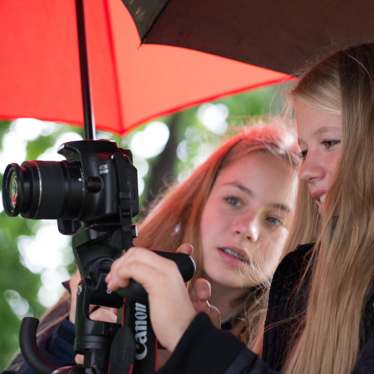 zwei Mädchen fotografieren unterm Regenschirm