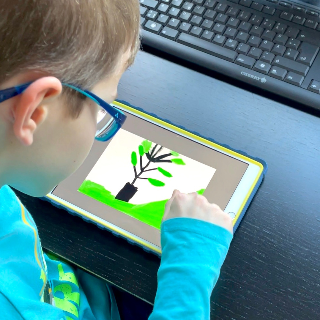 Ein Junge malt ein Bild auf dem iPad.