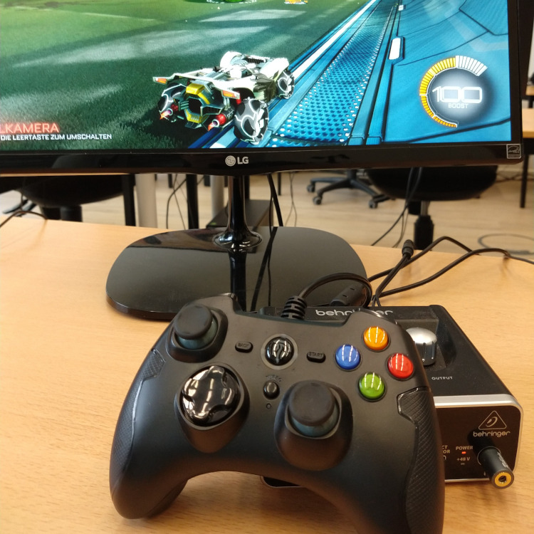 Spielecontroller vor PC, auf dem das Spiel "Rocket League" läuft